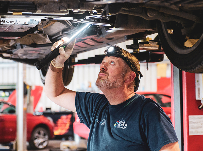 Underside of a car being looked at by vehicle technician