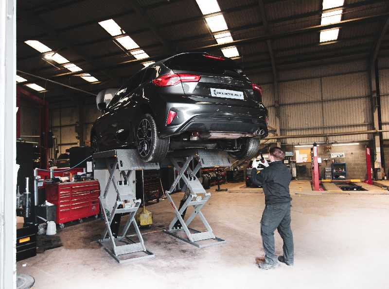Grey Ford on a ramp with a technician recording a video health check