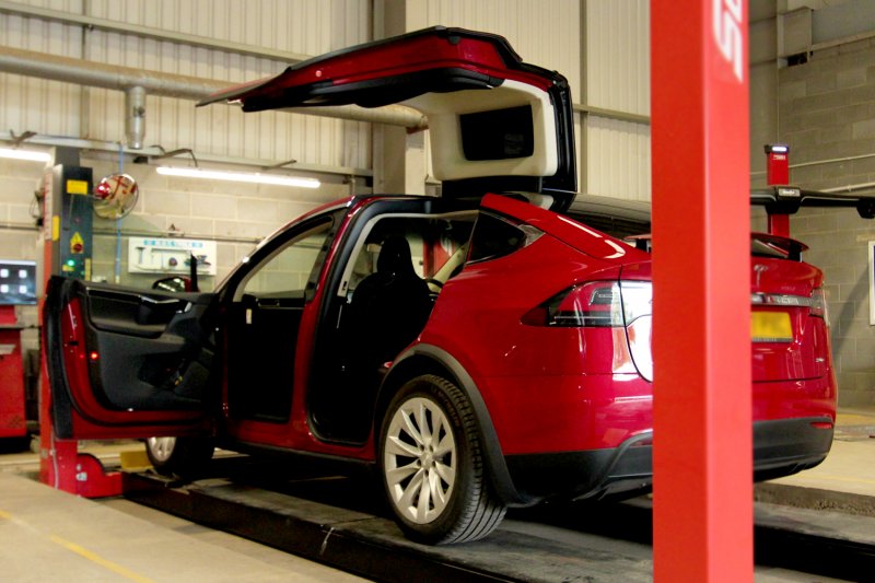 Red Tesla on MOT ramp with front door and gull back door open