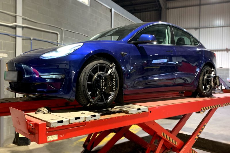 Blue Tesla on the wheel alignment ramp
