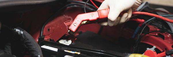 Car battery being charged with jump leads